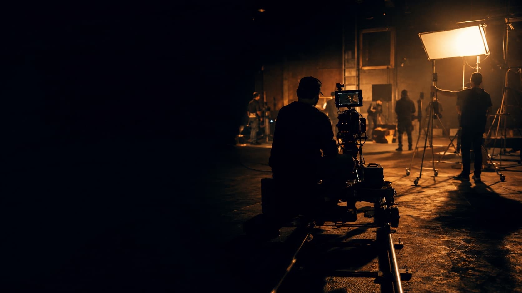 A film crew working around a lit set at night.